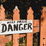 danger signage on brown wooden rail