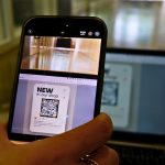 a person holding a cell phone in front of a laptop